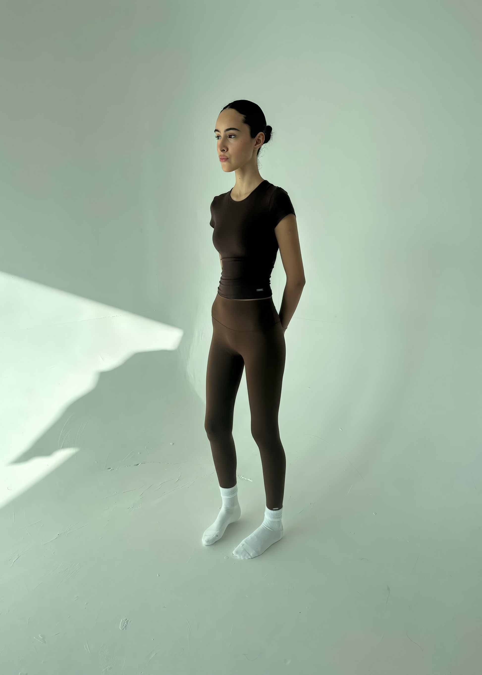 Person wearing a black outfit standing against a white background