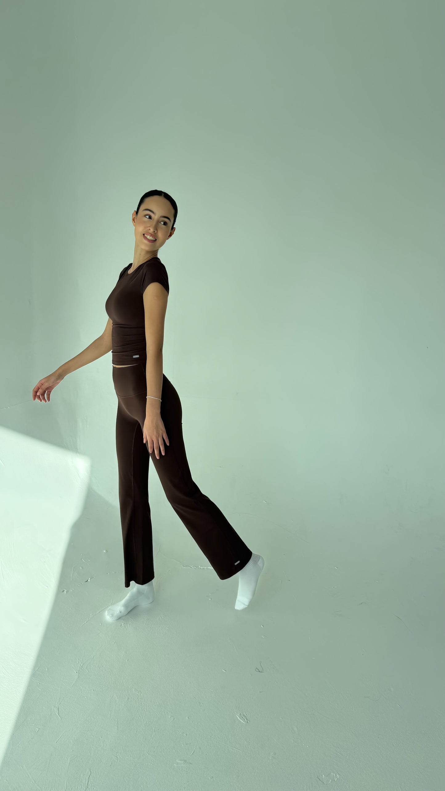 Person wearing a brown outfit standing against a plain background