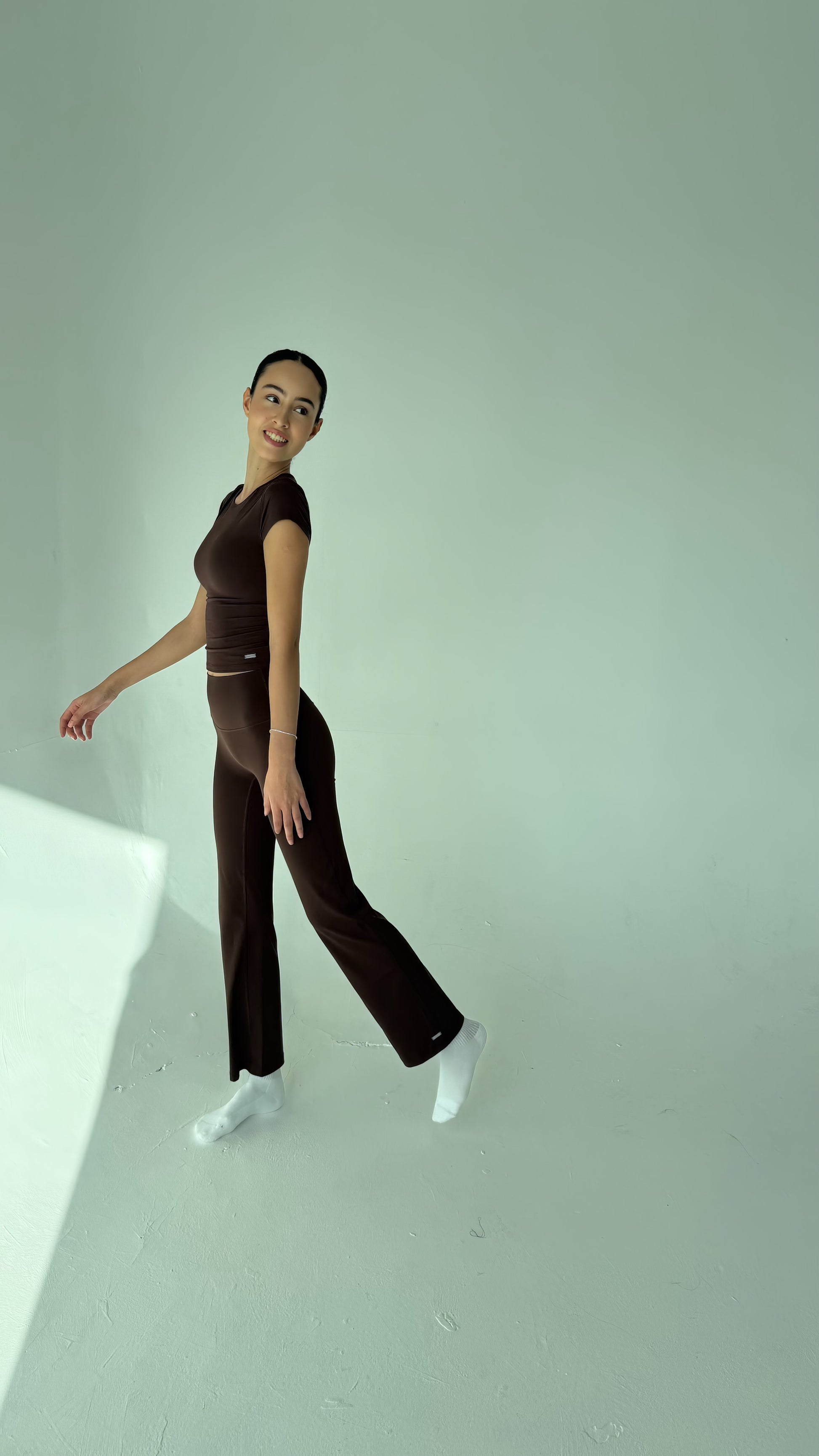 Person wearing a brown outfit standing against a plain background