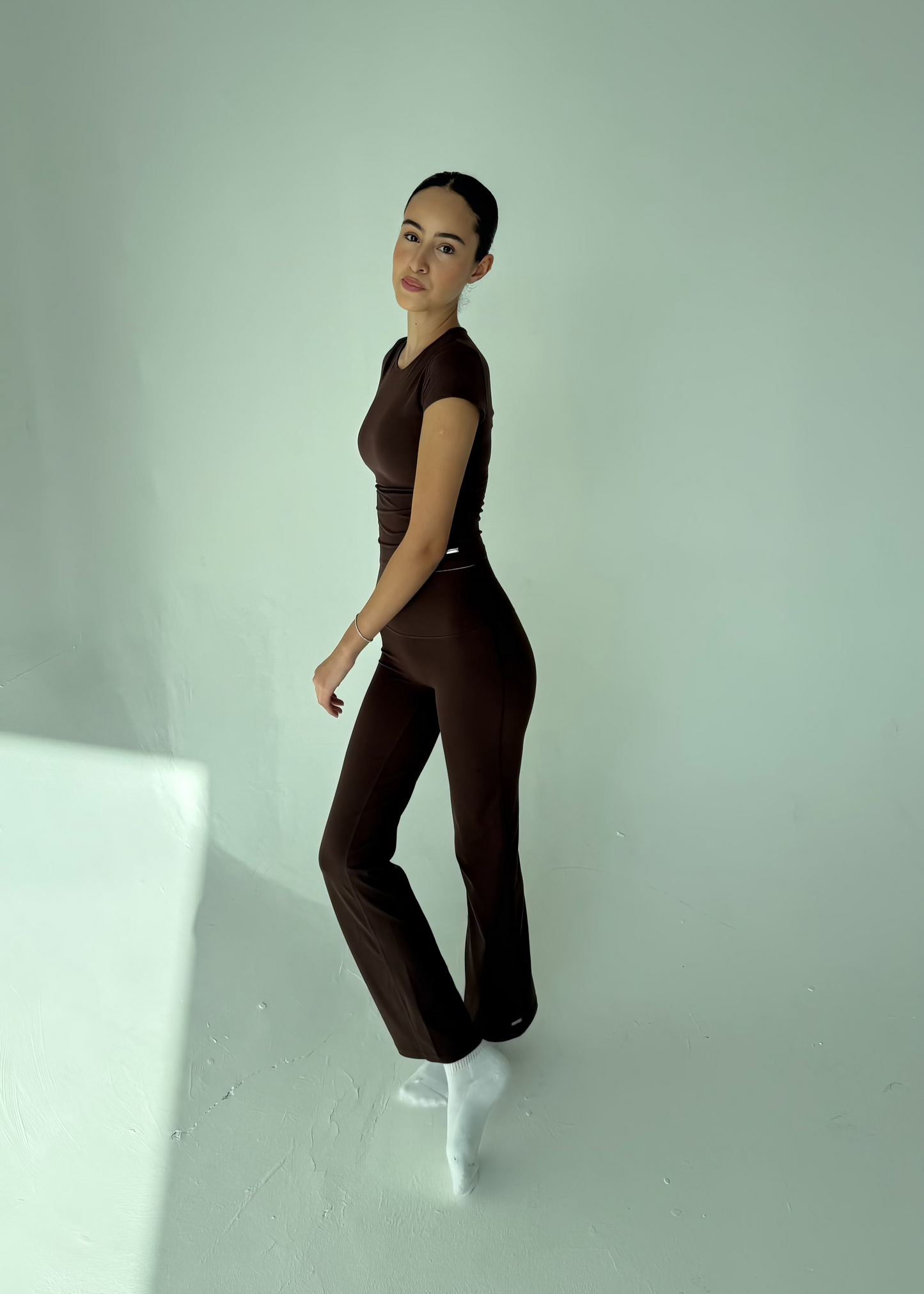 Person wearing a brown outfit standing against a white background