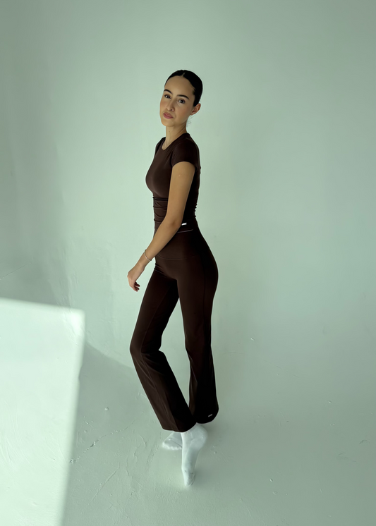Person wearing a brown outfit standing against a white background