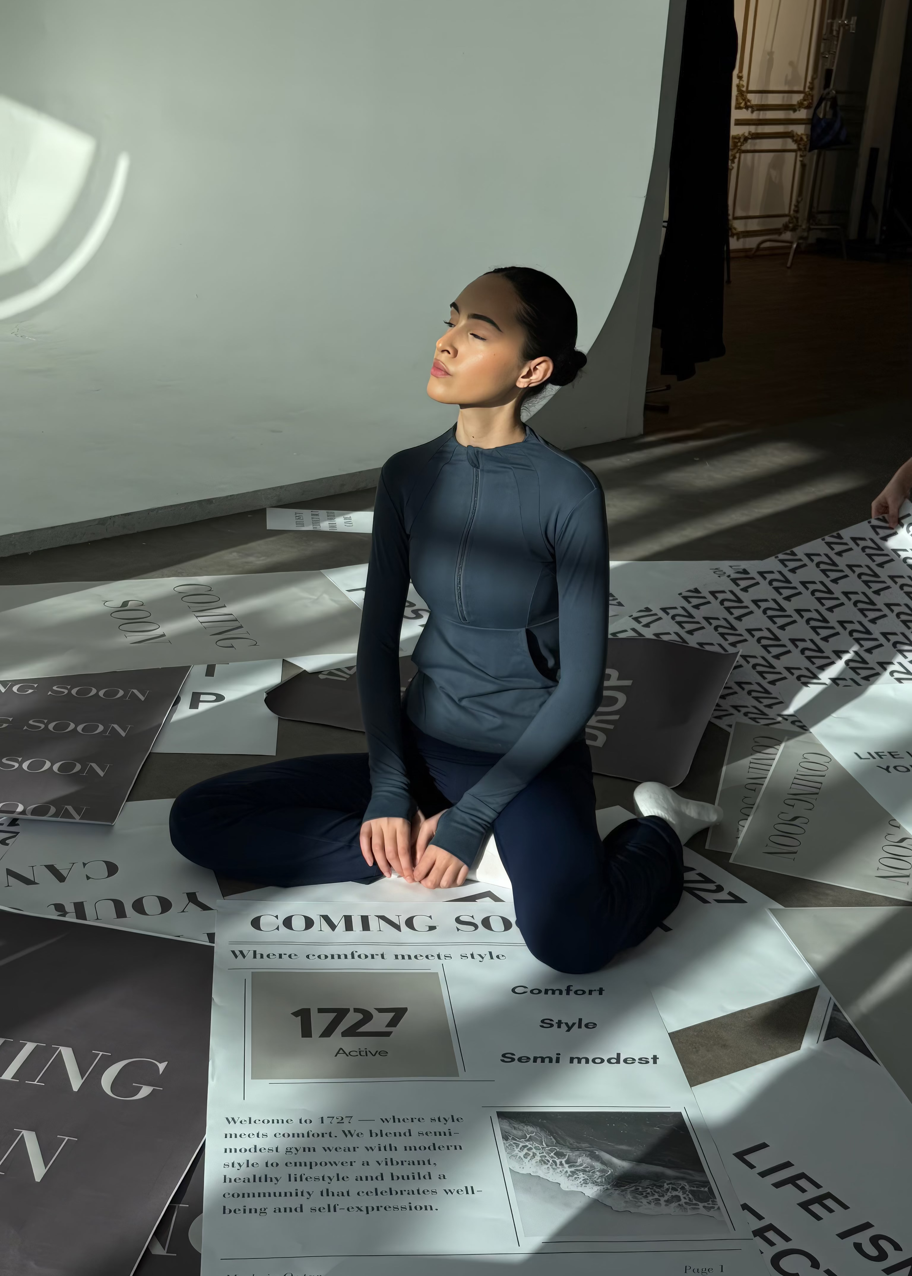 Person sitting on a floor with newspaper spread out, wearing a dark blue outfit.